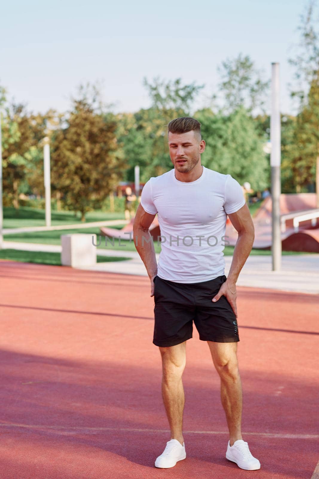 athletic men doing exercises on the sports ground in summer by Vichizh