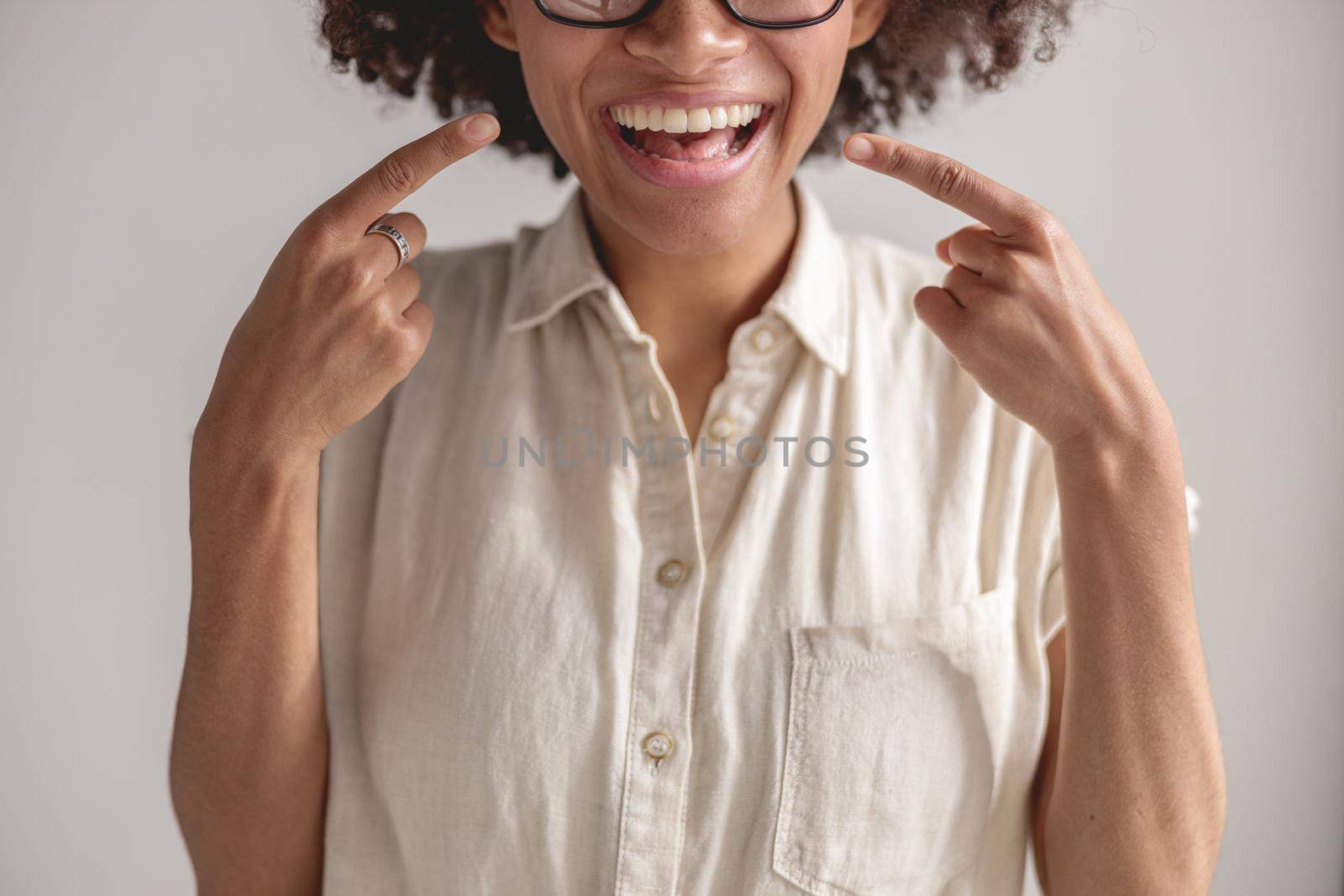 Cropped photo of happy Afro American woman pointing her fingers at smile, isolated on grey background