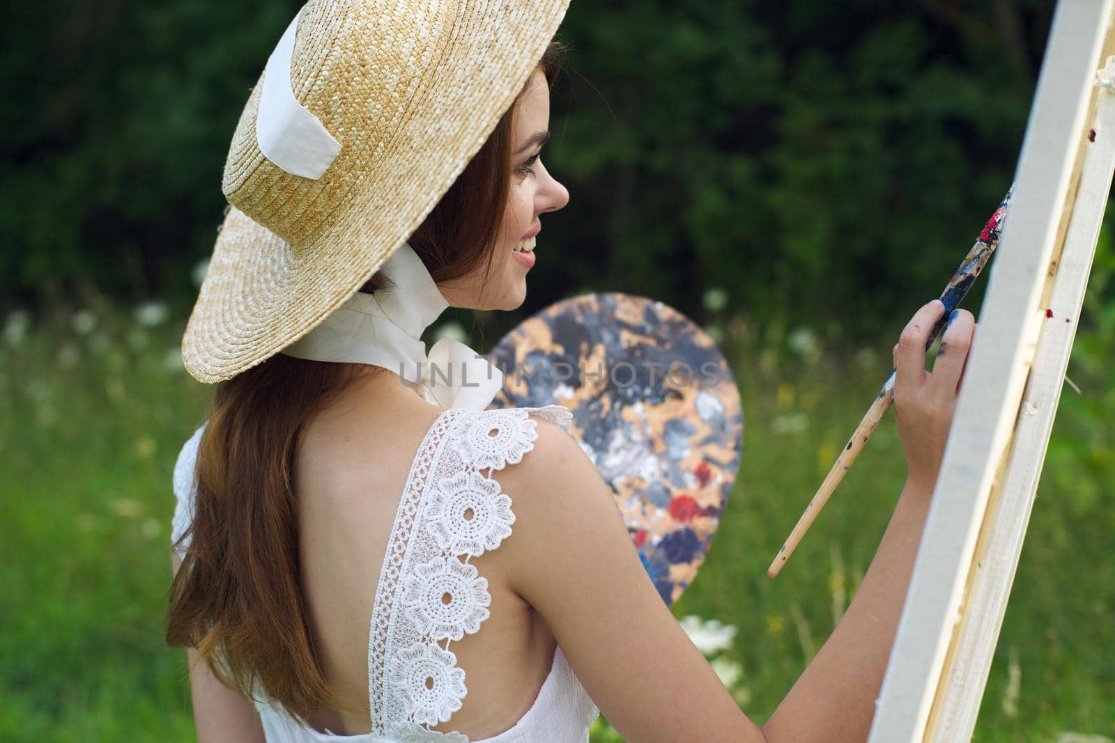 woman with a palette of paints painting a picture outdoors close-up. High quality photo