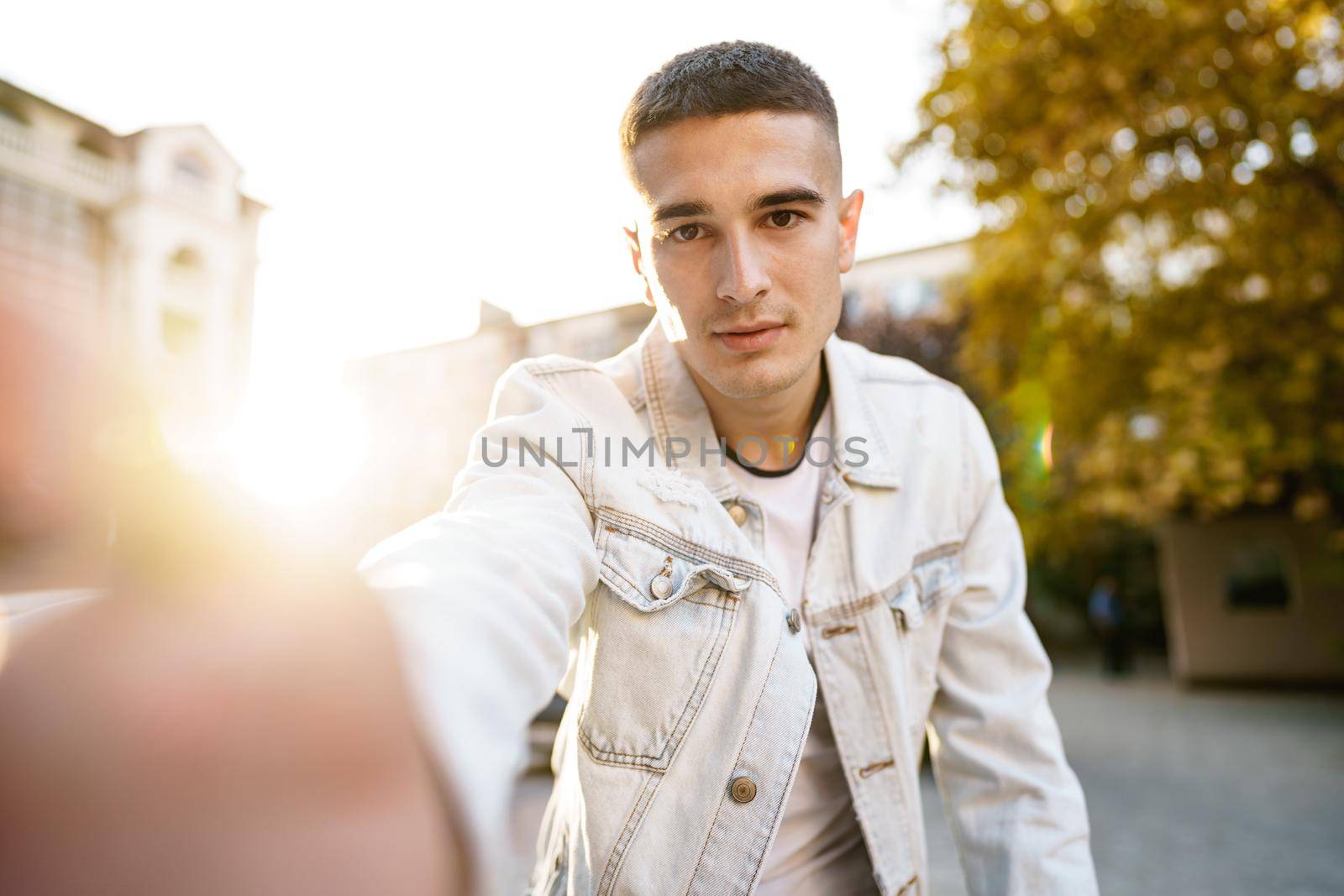 Portrait of young man taking a selfie while out on the city street, close up selfie