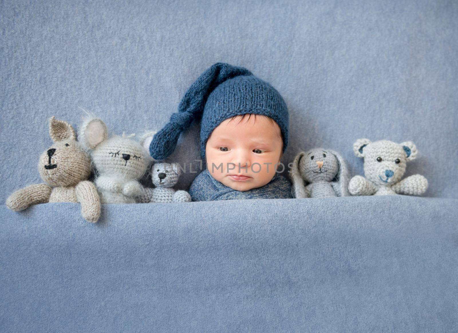 Cute newborn boy lying under blue blanket by tan4ikk1