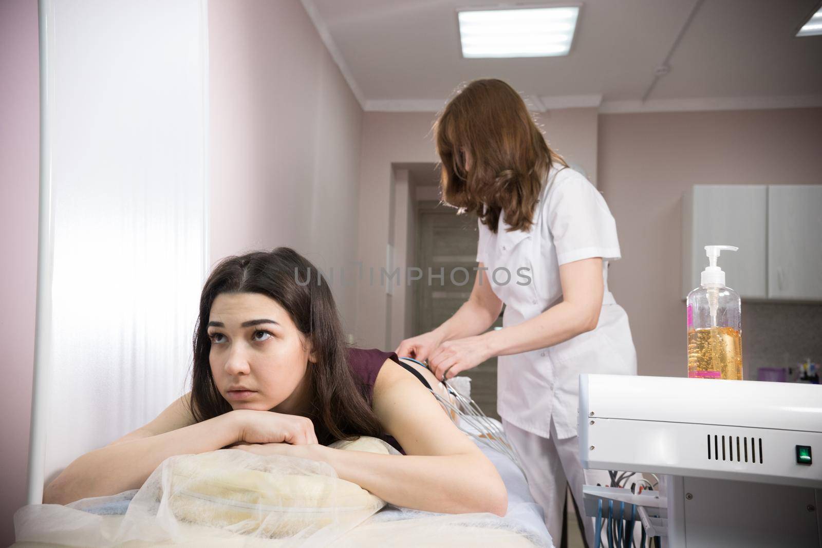 cosmetology beauty clinic. young woman taking myostimulation and doctor preparing the procedure at the nutritionist's office by Studia72