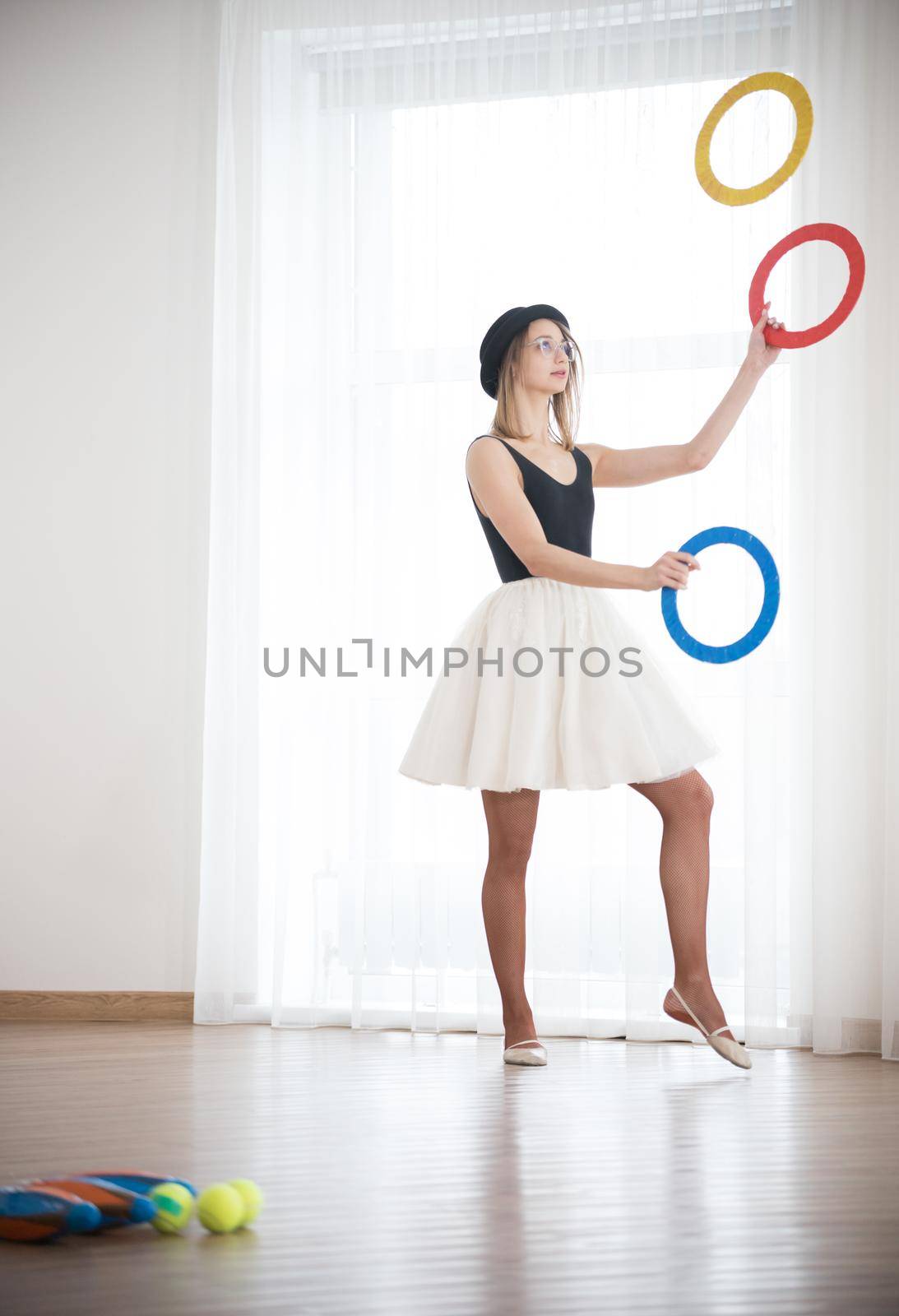 Girl in a hat juggles with rings in the studio, elephoto shot