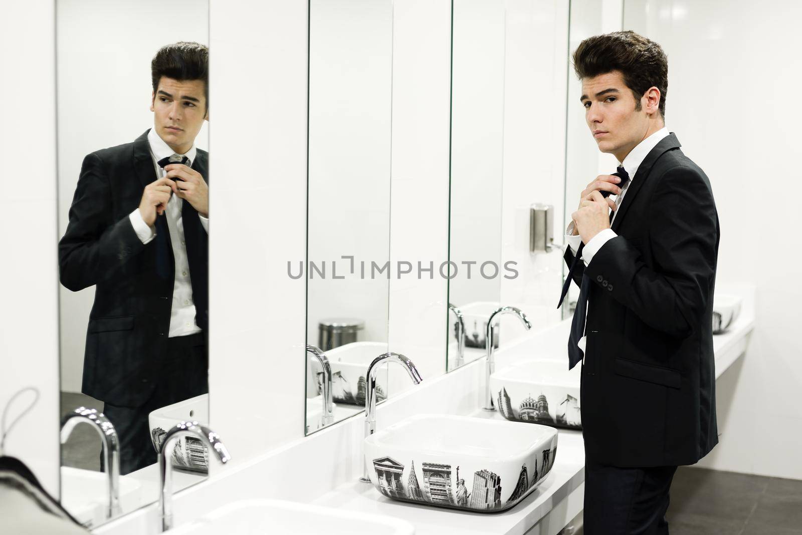 Man getting dressed in a public restroom with mirror by javiindy