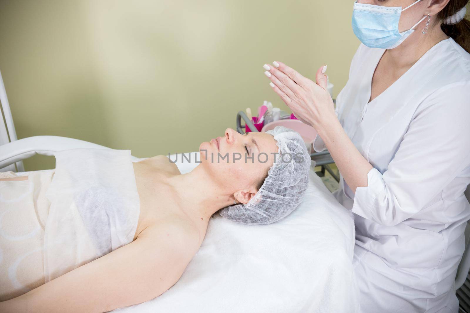 Cosmetologist prepares the client's face for cosmetic procedure of mesotherapy. Mid shot
