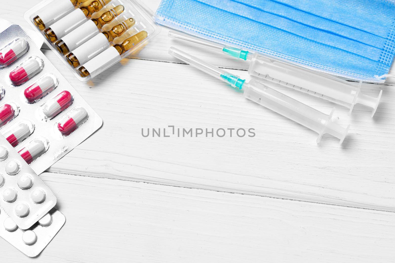 Medical capsules, ampules and face masks close up on wooden background