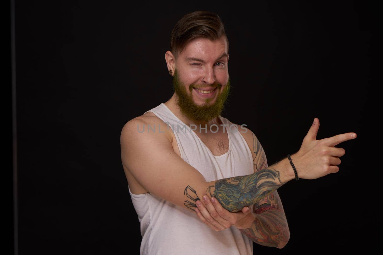 bearded man with tattoos on his arms gesturing with his hands dark background by Vichizh