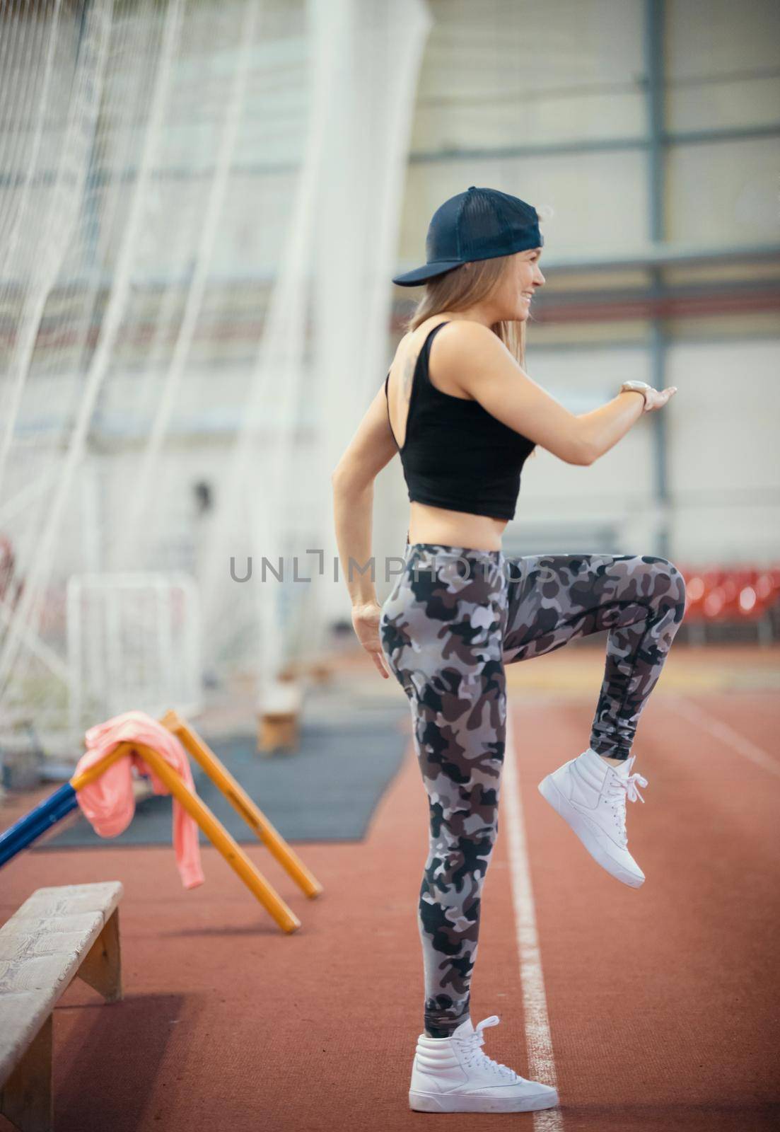 Young athletic woman in leggings warming up her legs. Mid shot