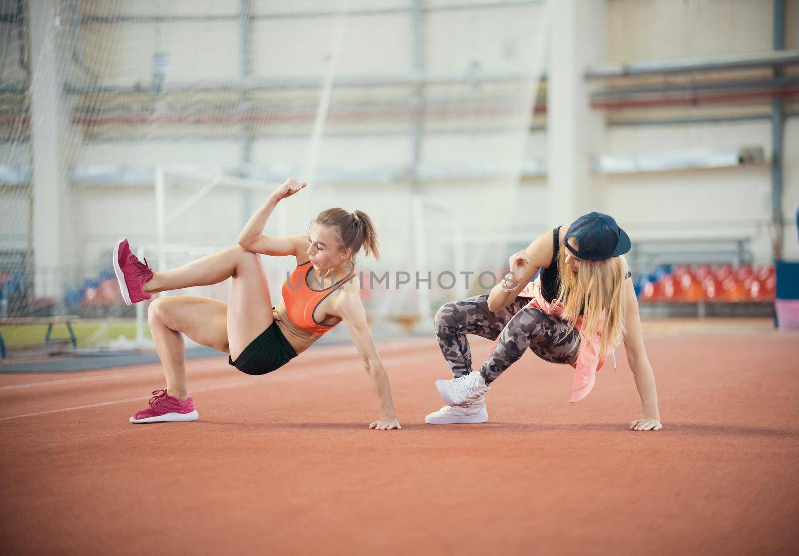 Two young athletic woman working out. Synchronously make movements. Mid shot