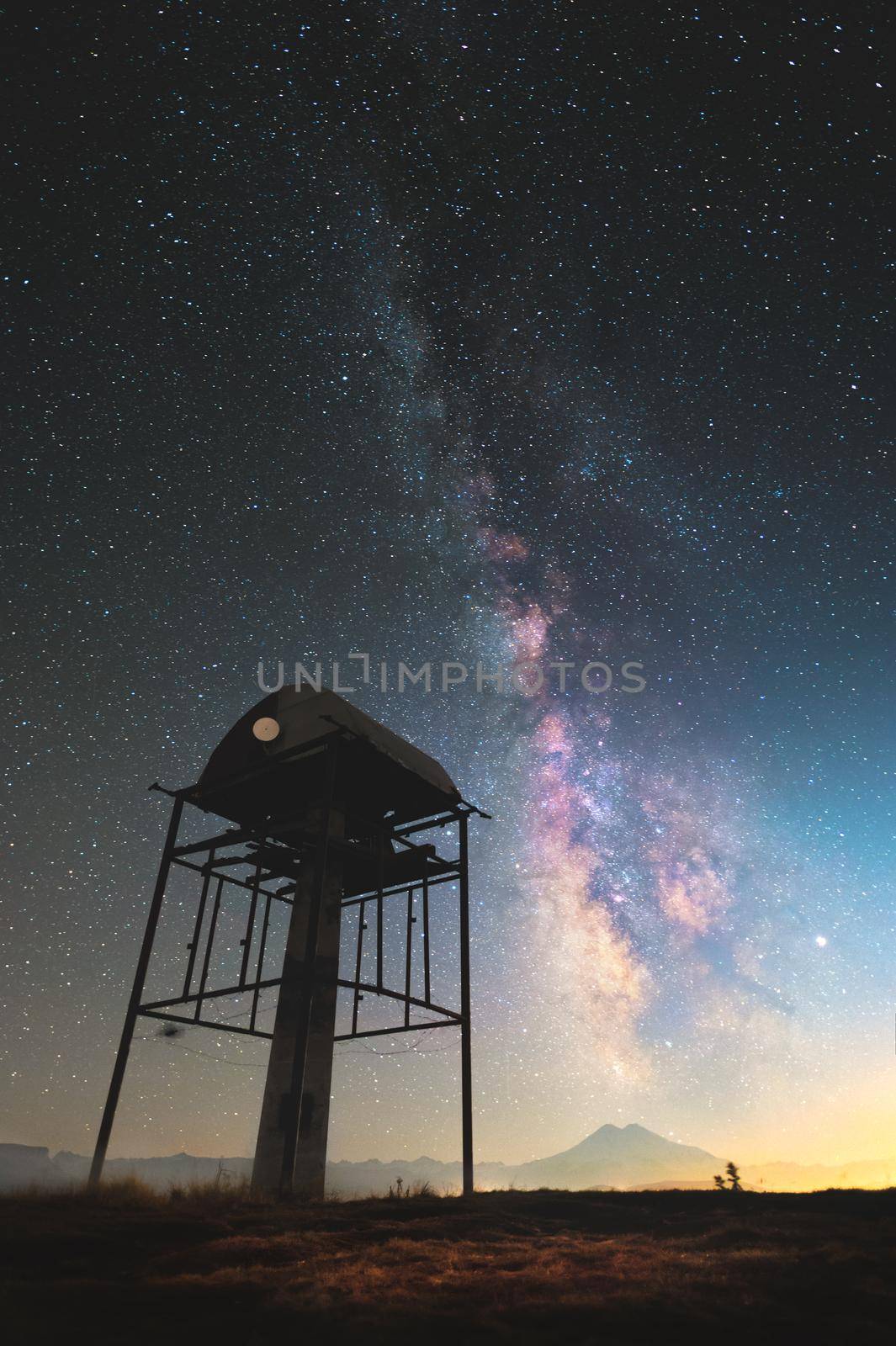 Night landscape of the starry sky and the Milky Way with a telecommunication tower for transmitting wifi in the mountains. against the backdrop of Mount Elbrus in the North Caucasus...