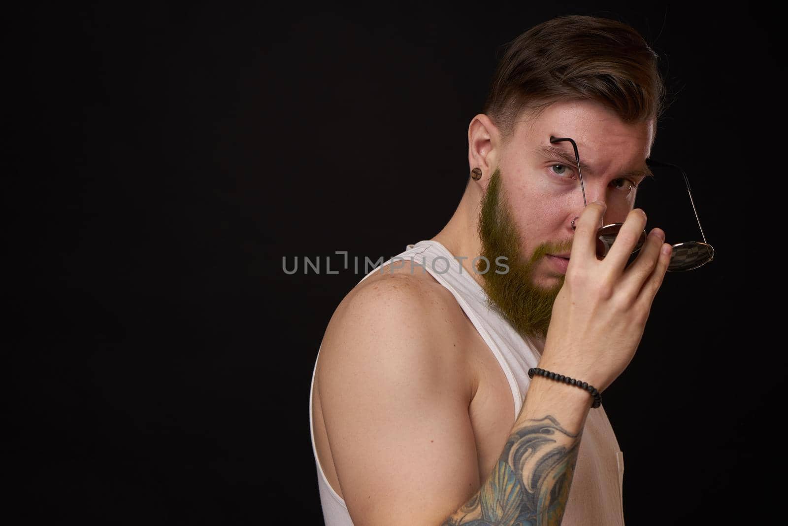 bearded man in white t-shirt with tattoos on his arms posing bully. High quality photo