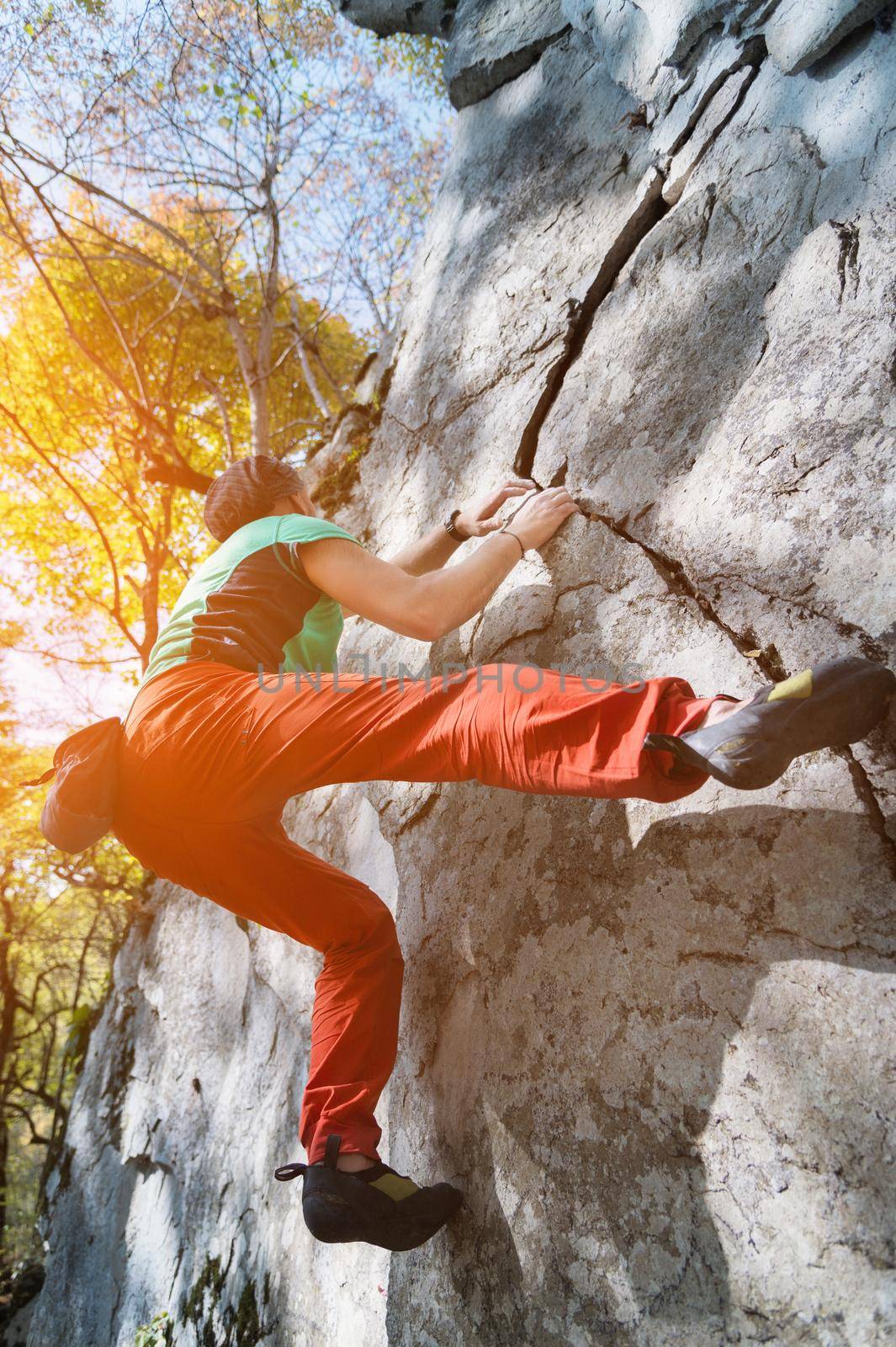 A free aged male climber hangs on a rock wall in a forest in the mountains. Mature Sports Concept by yanik88