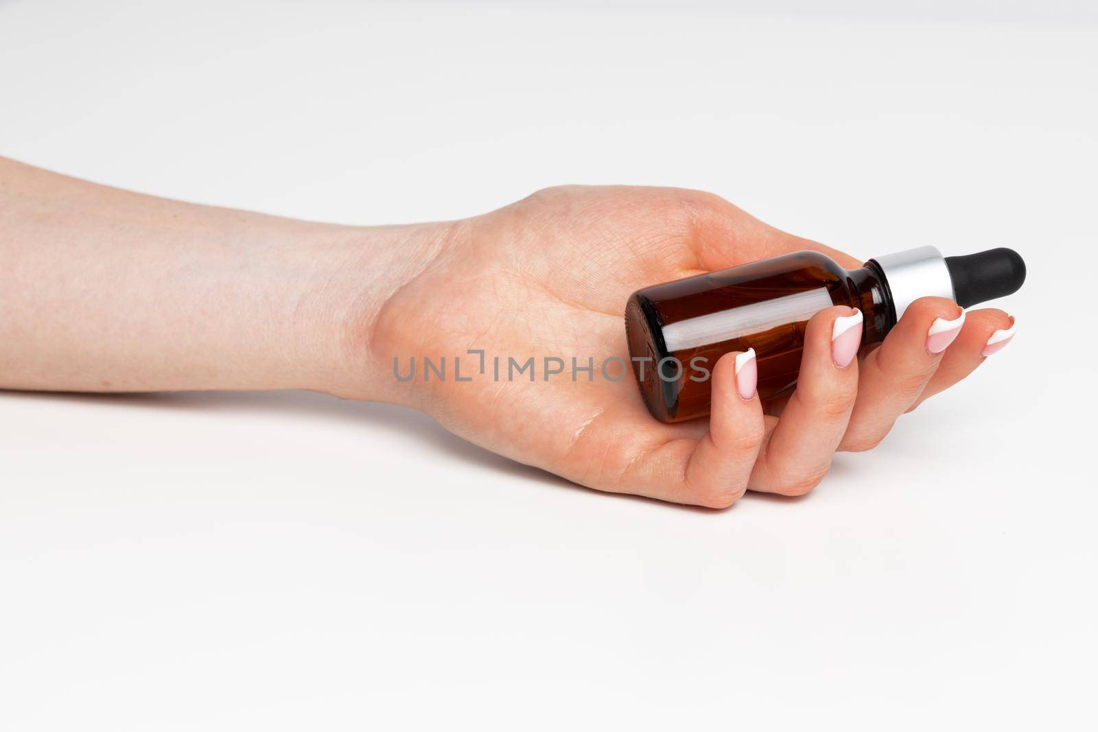 Female hand holding cosmetic bottle on white background