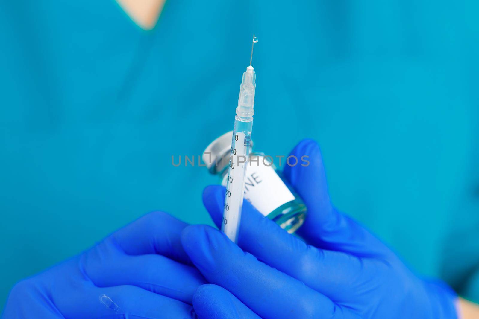 Doctor hands in blue gloves holding covid-19 vaccine preparing for vaccination of a patient