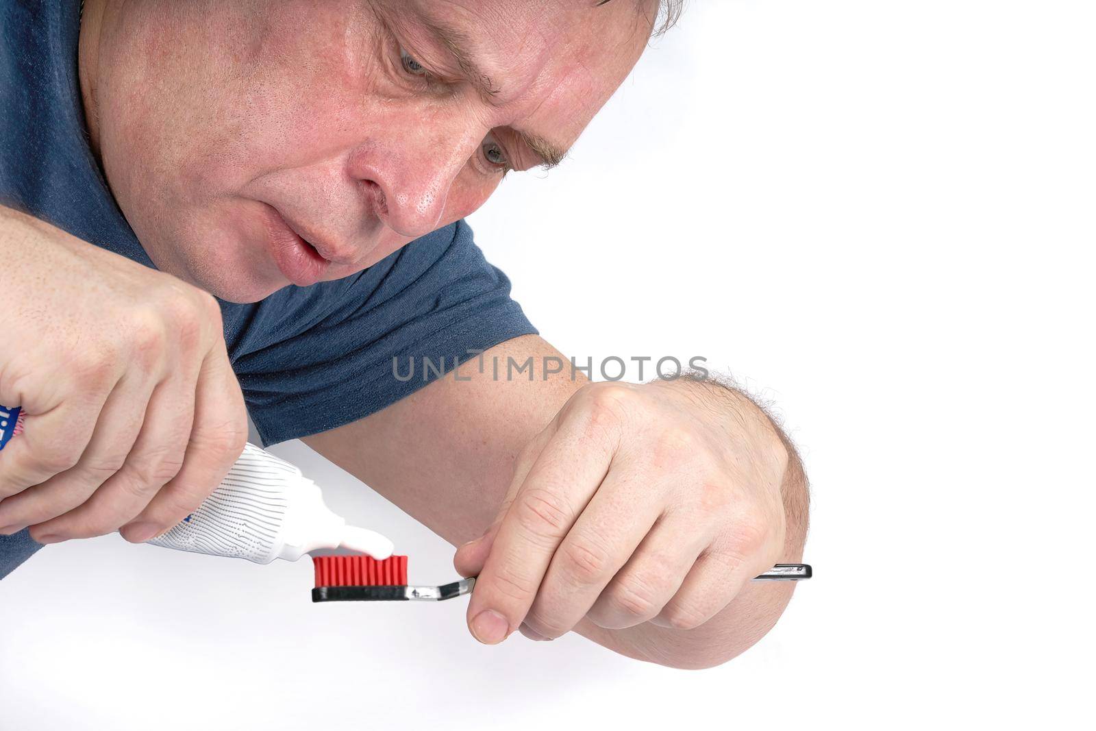 Man squeezes toothpaste onto black toothbrush with red shield on white background