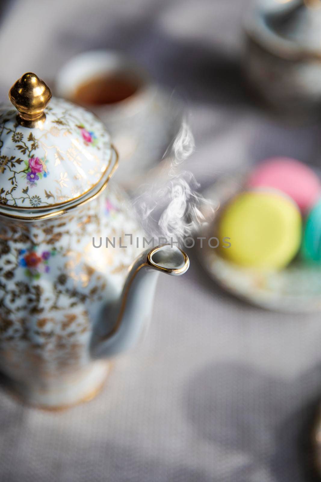 Traditional antique tea pot English culture afternoon tea with hot tea and smoke on diner table, vintage high tea concept elegant stylish set beauty