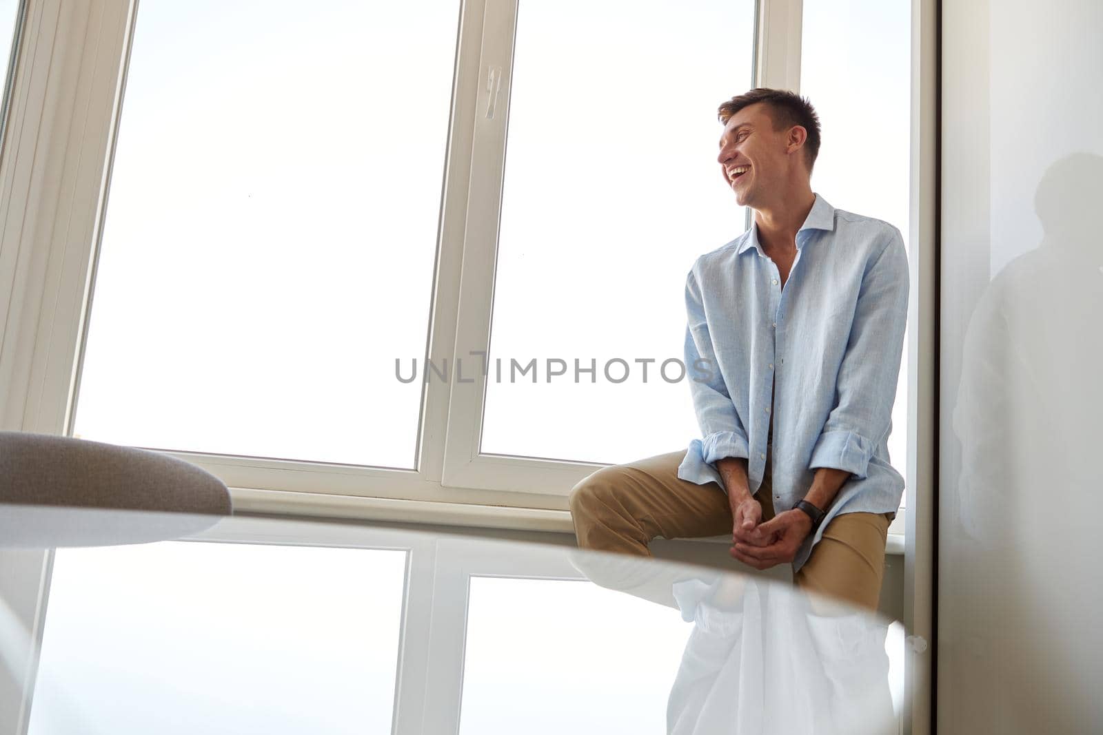 Happy beautiful handsome smiling caucasian man is relaxing at modern light home