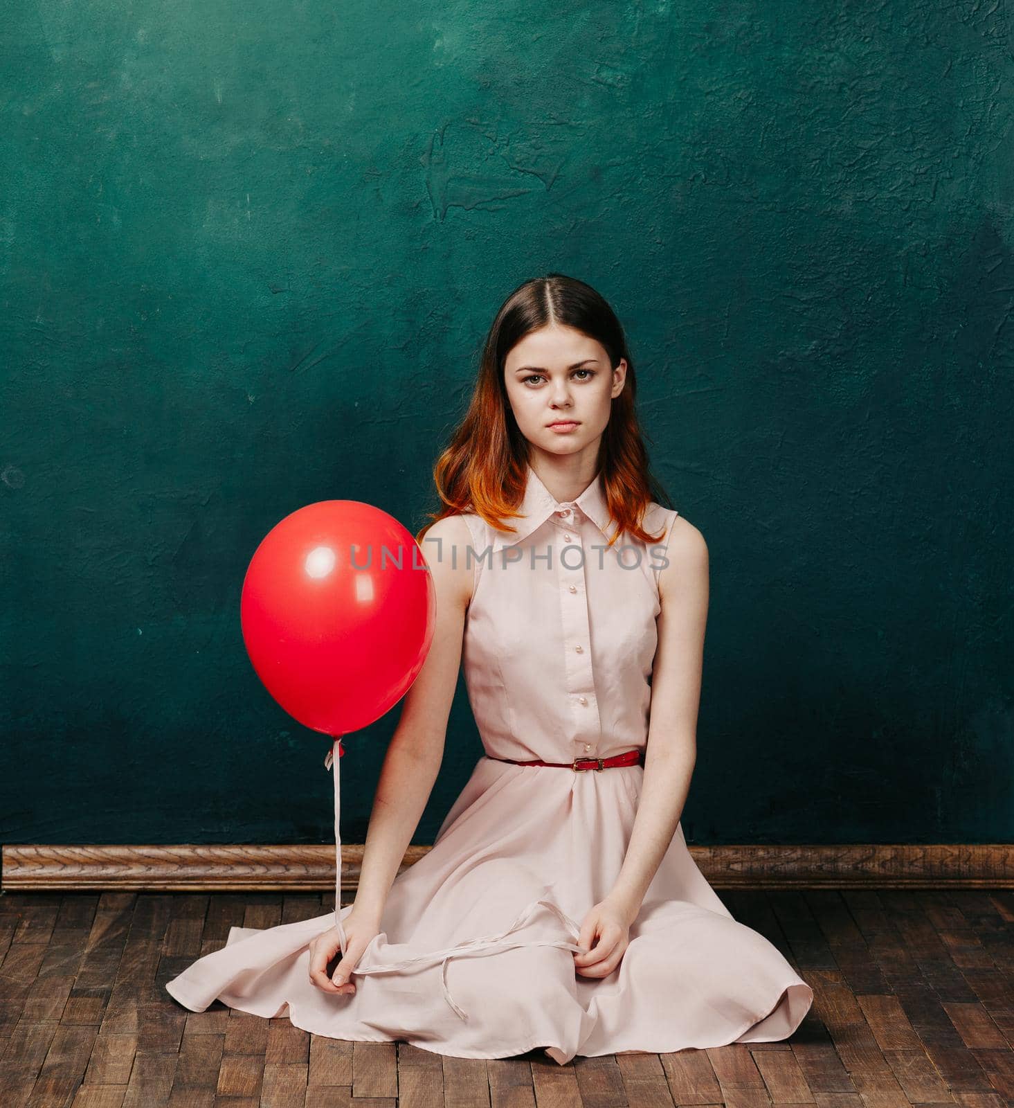 woman with red balloon on green background holiday fun. High quality photo