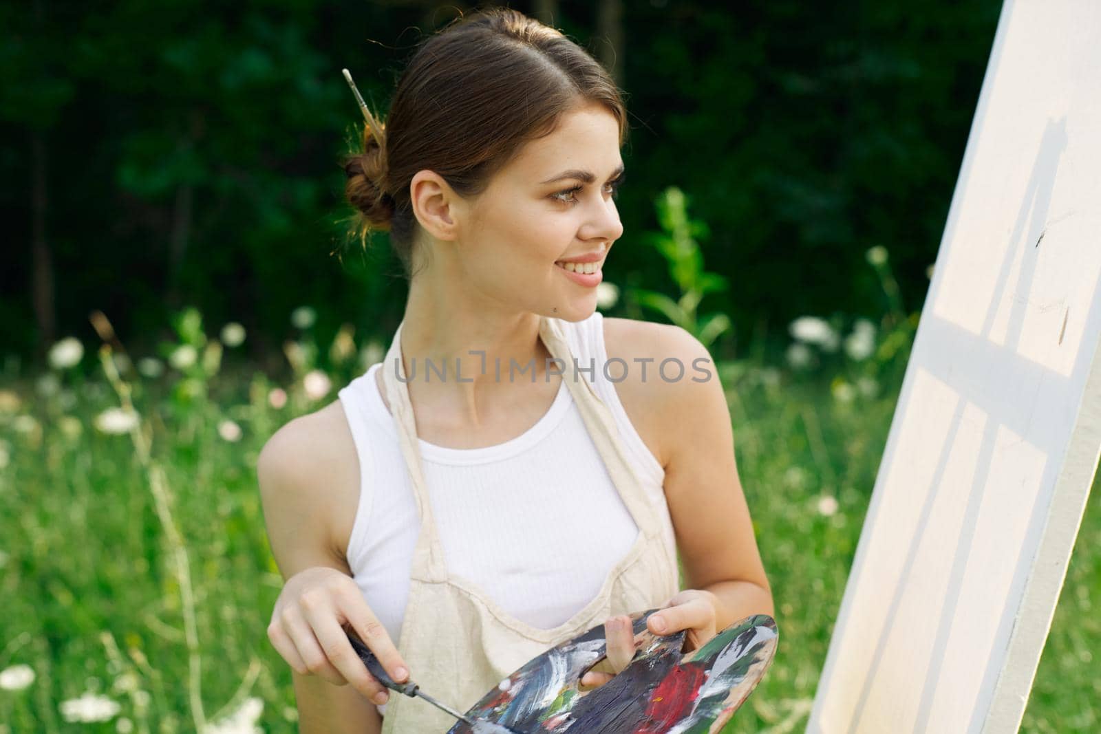 woman artist outdoors with palette of paints paints a picture by Vichizh