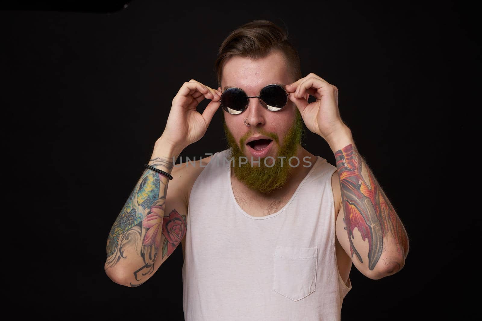 handsome man with tattoos on his arms fashion sunglasses dark background. High quality photo