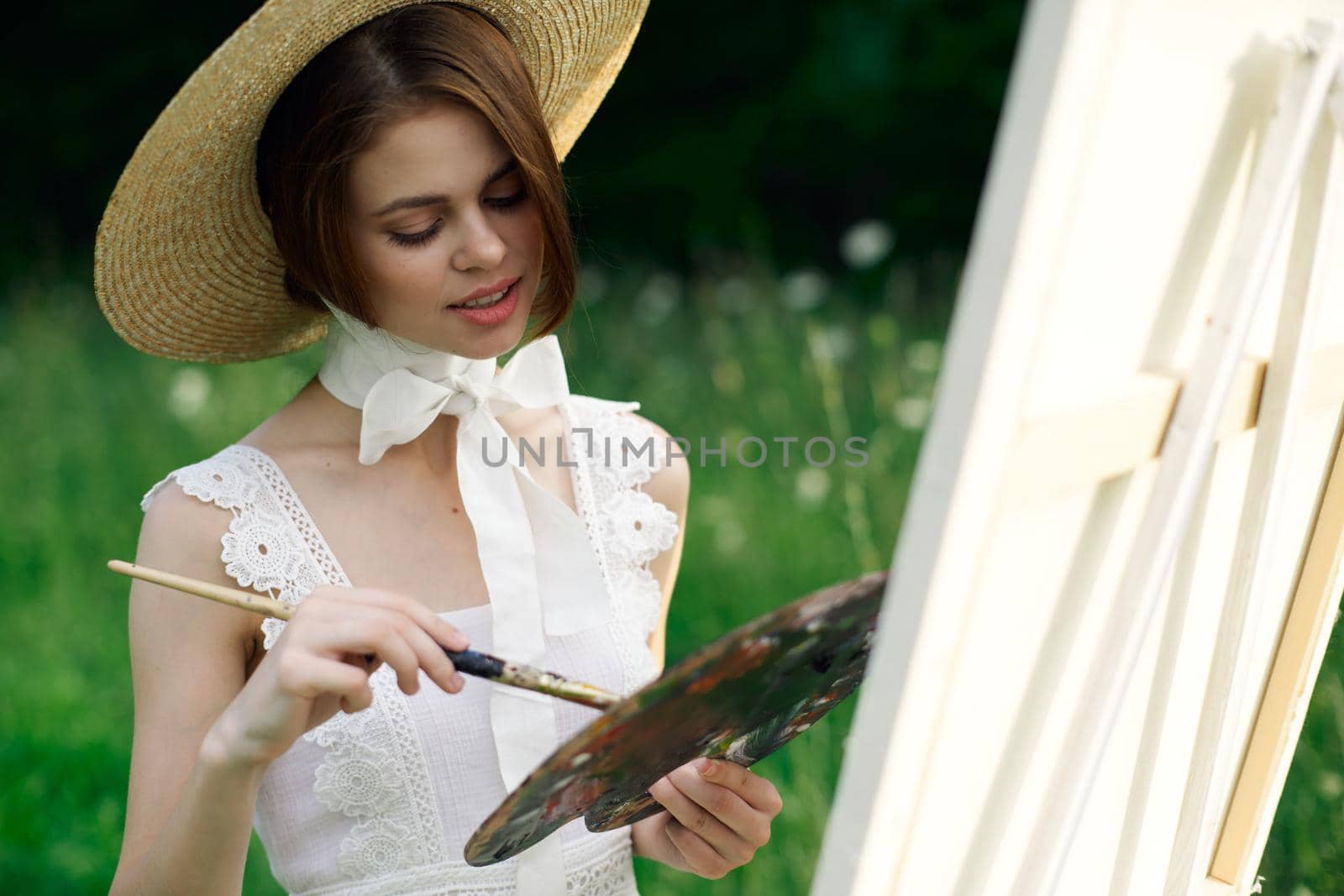woman artist view with paint palette draws a picture in nature. High quality photo