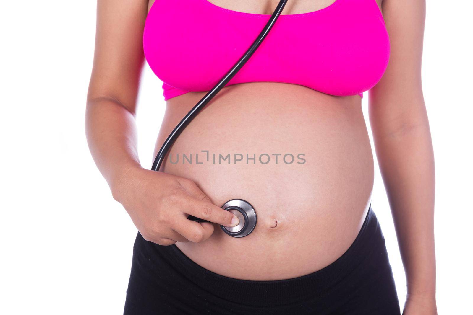 close-up of pregnant woman with stethoscope listening belly to baby