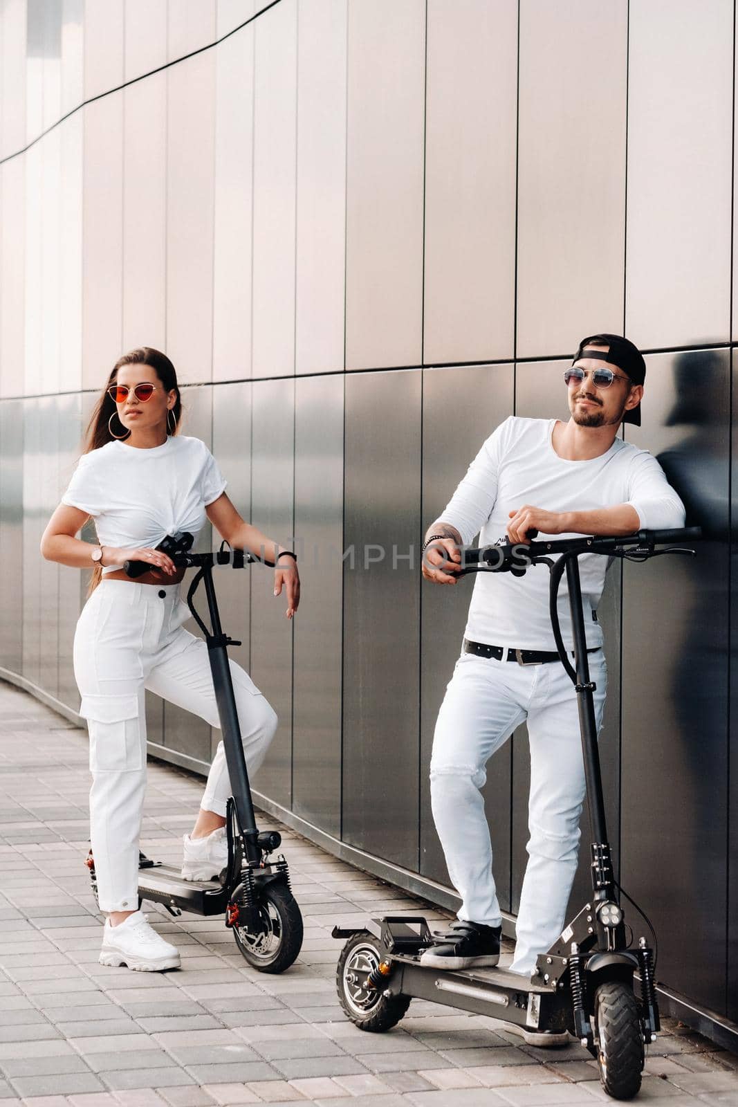 A couple on electric scooters ride around the city, a couple in love on scooters by Lobachad