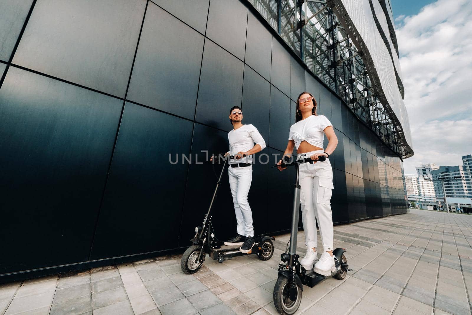 A couple on electric scooters ride around the city, a couple in love on scooters.