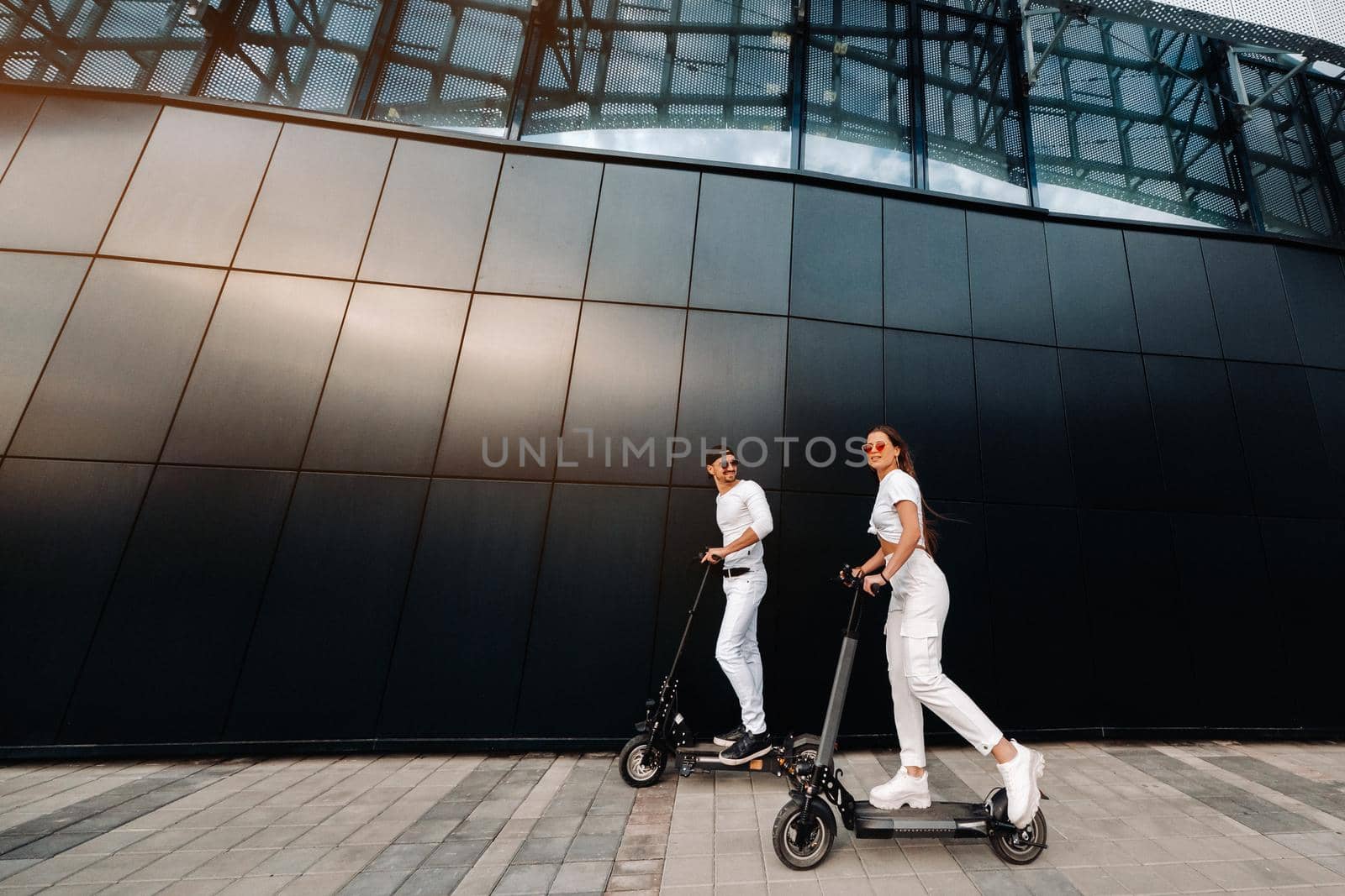 A girl and a guy are walking on electric scooters around the city, a couple in love on scooters