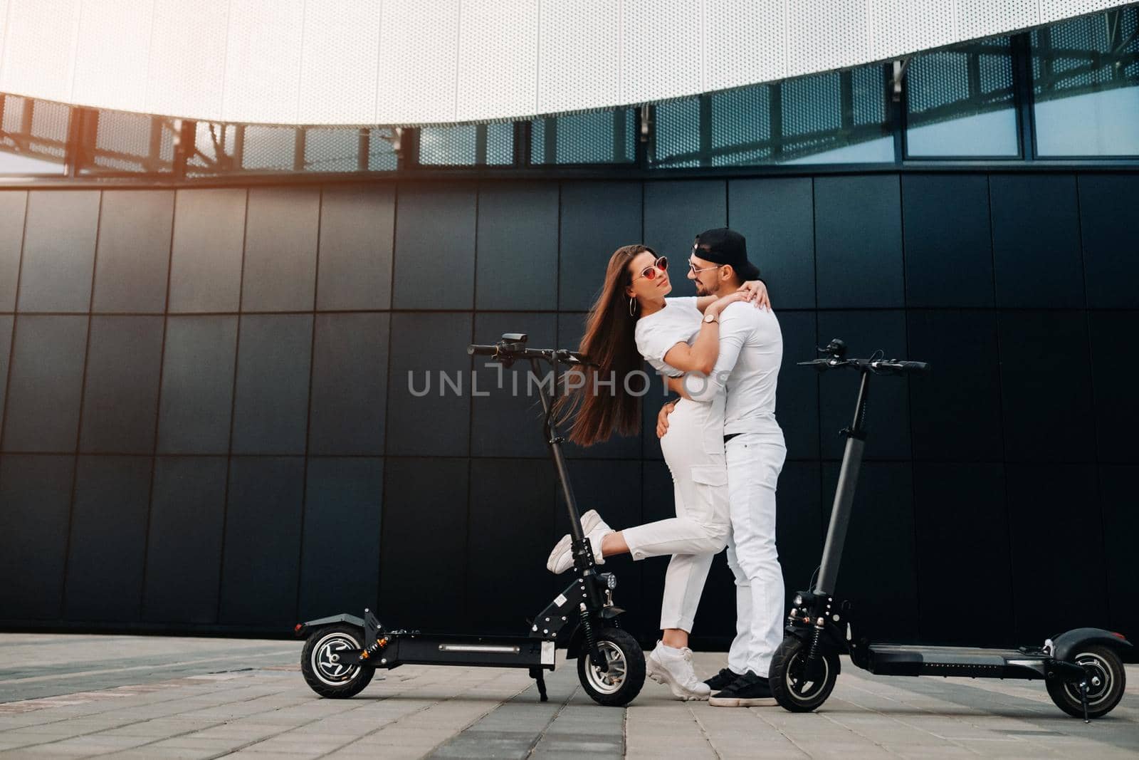 A couple on electric scooters embrace in the city, a couple in love on scooters.