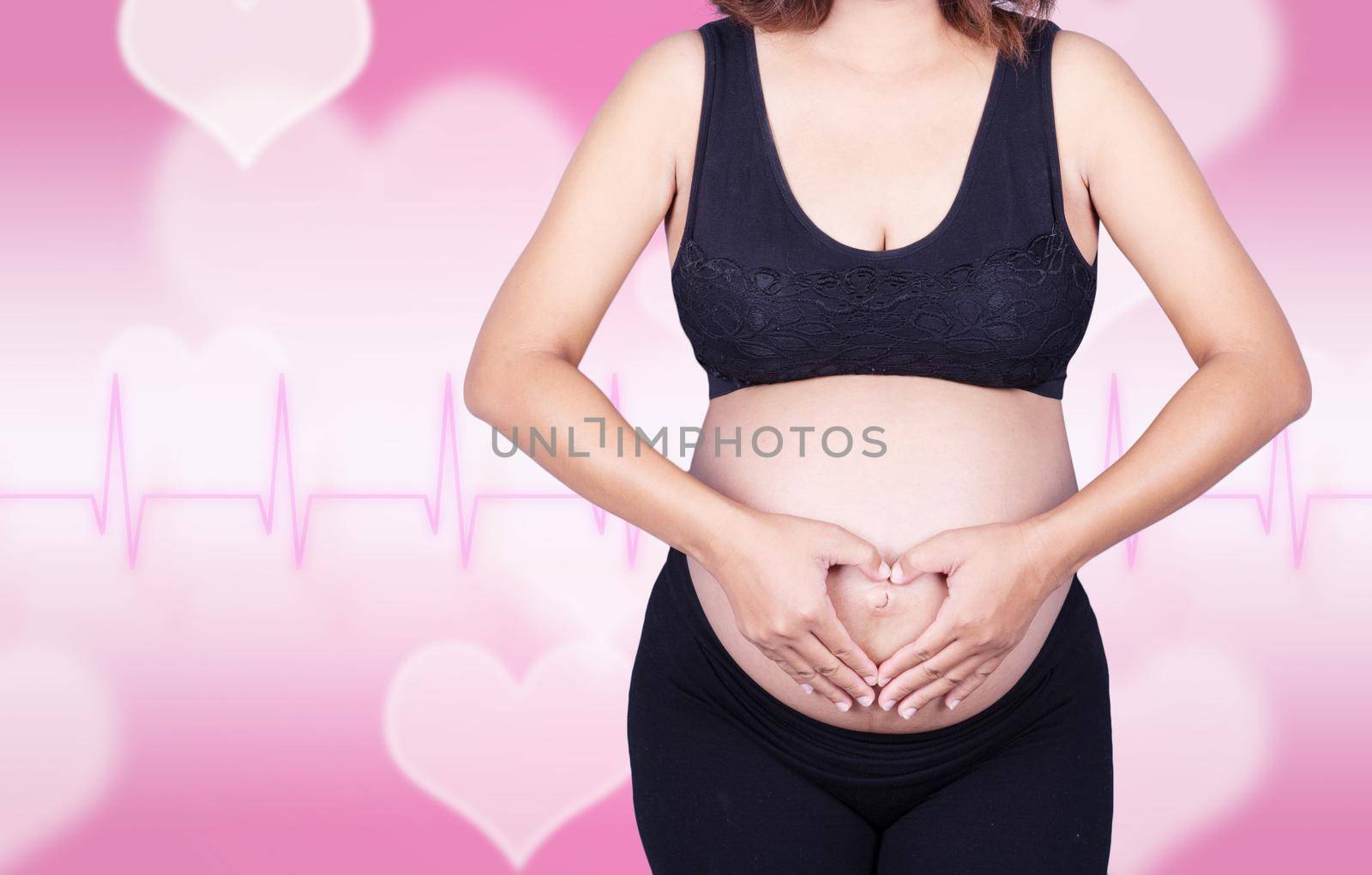 Pregnant Woman holding her hands in a heart shape on her belly on heart background