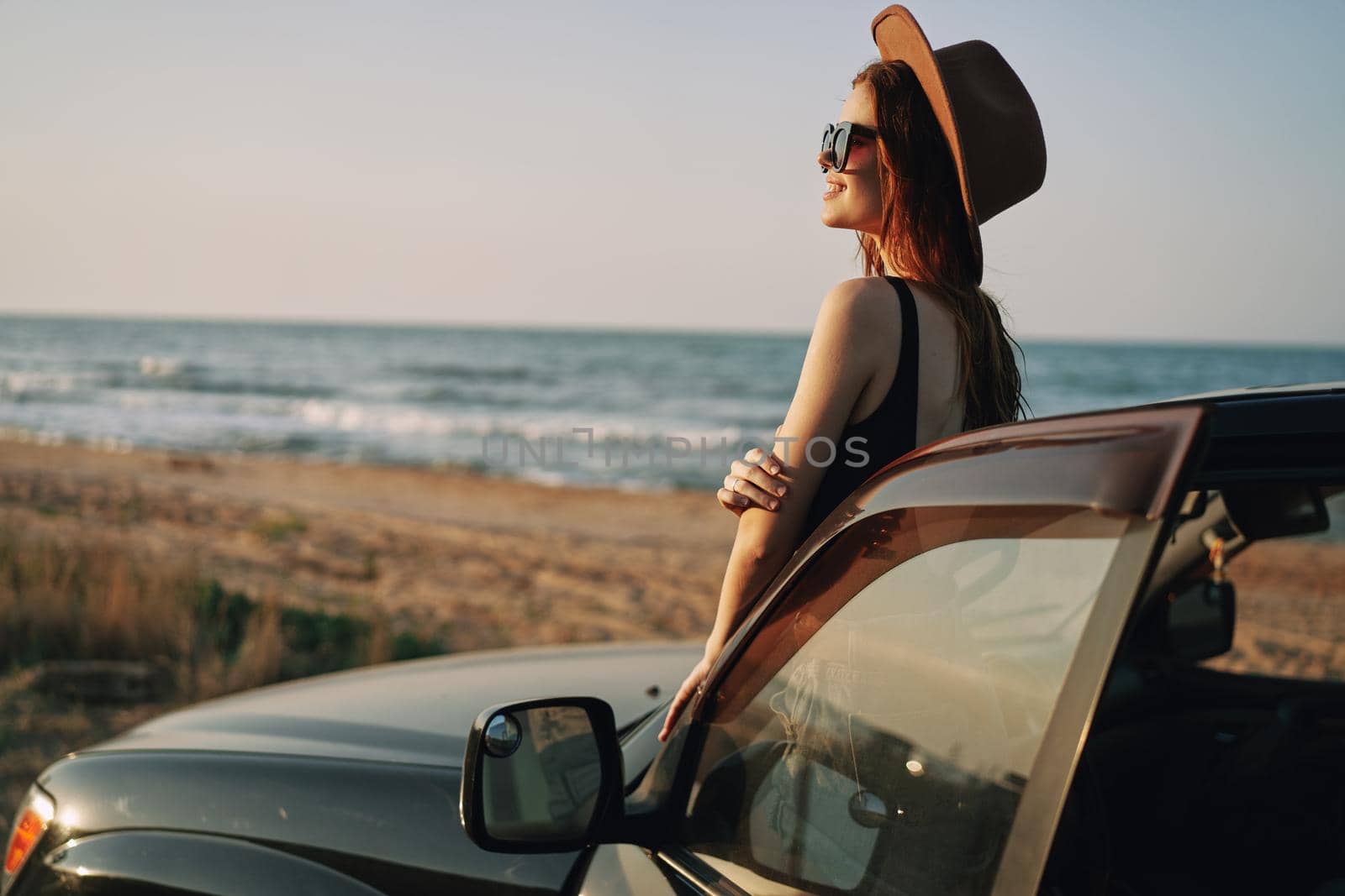 pretty woman in sunglasses near the car on the beach travel lifestyle. High quality photo