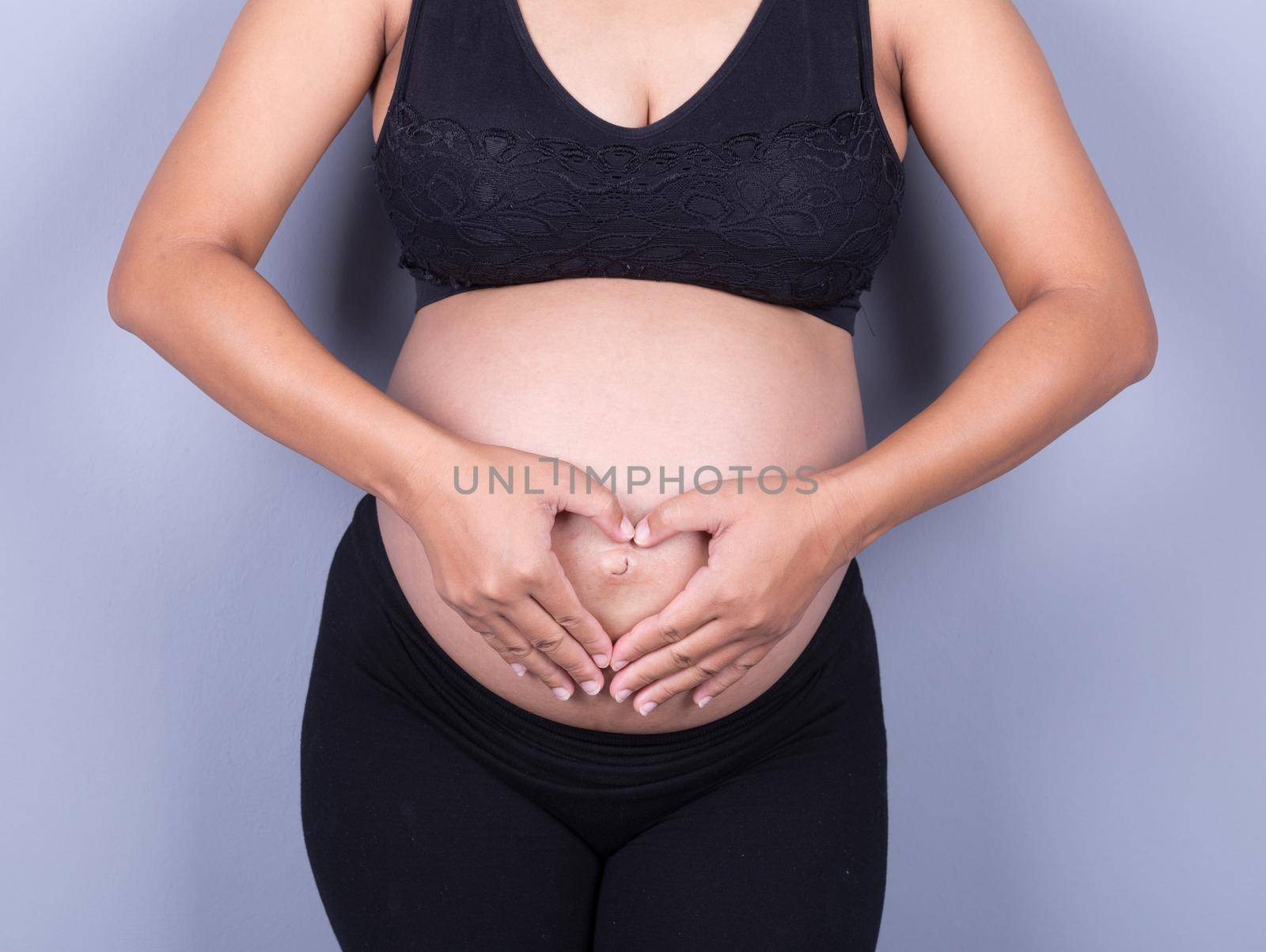 Pregnant Belly of woman with fingers Heart shape