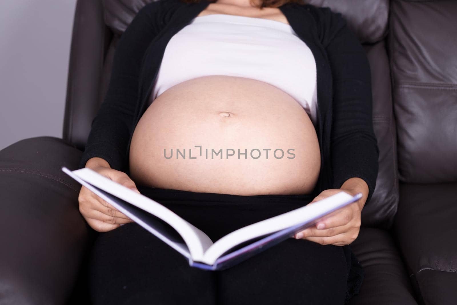 close up pregnant woman lying on sofa and reading book by geargodz