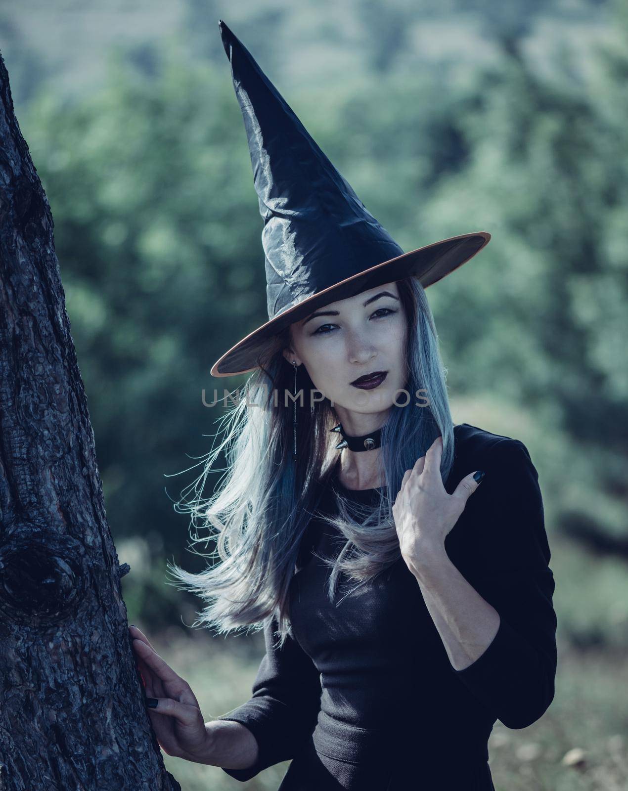 Beautiful young woman in costume of witch walking in autumn forest, Halloween theme