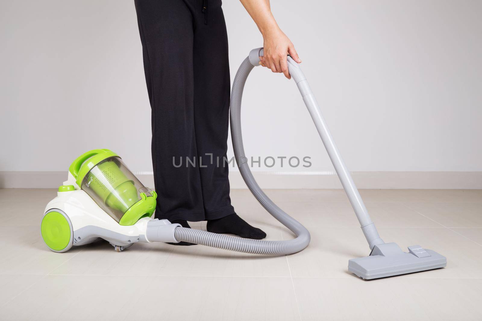 woman legs with vacuum cleaner cleaning floor at home