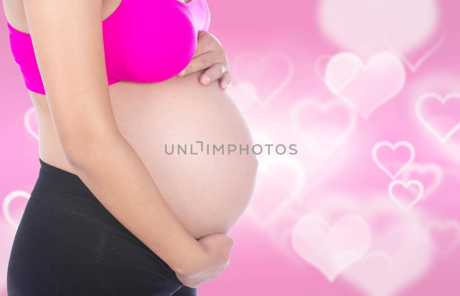 Close-up of pregnant woman belly with her hand on it on heart backrground by geargodz