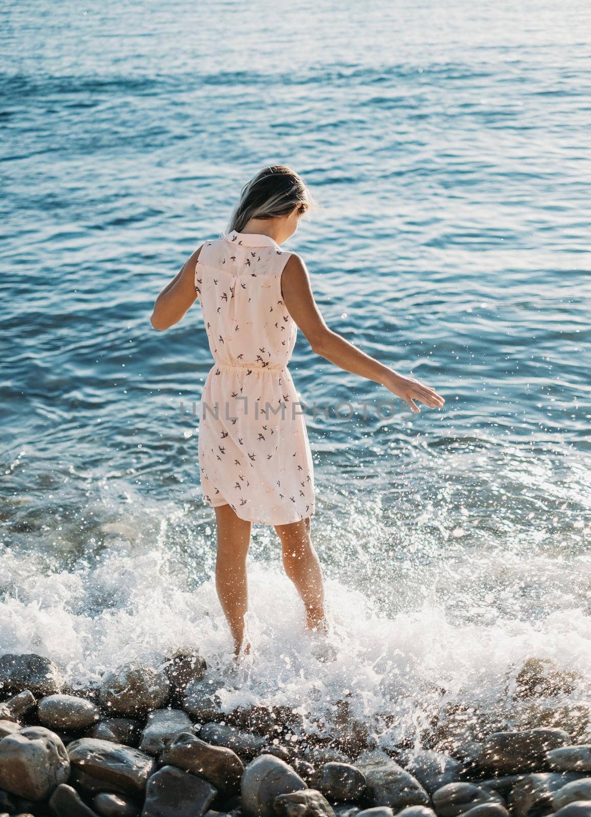 Young woman walking on coastline near sea waves
