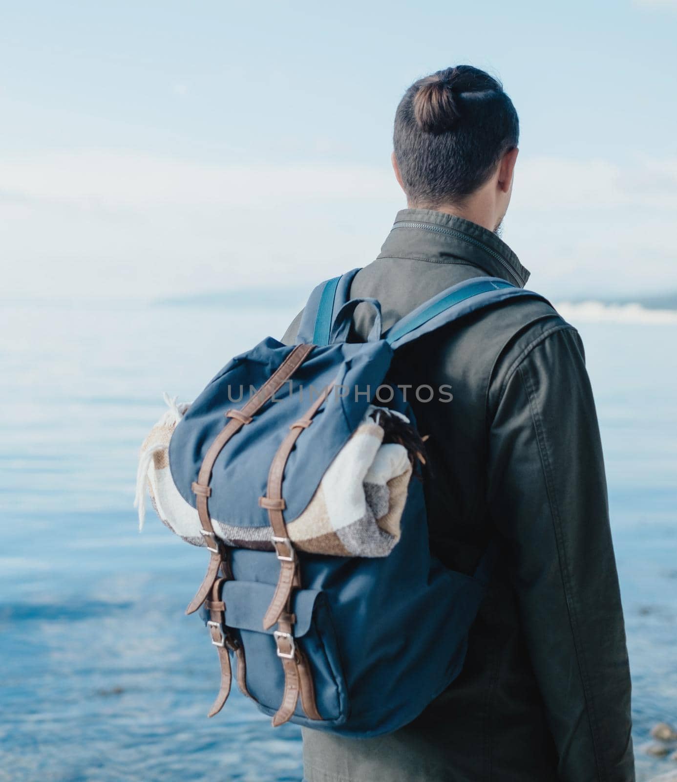 Unrecognizable traveler young man with backpack looking at sea