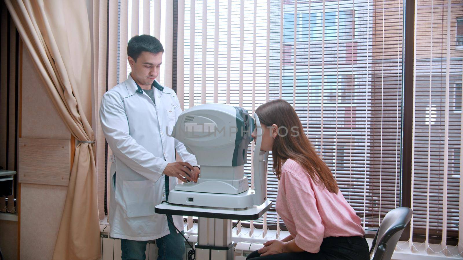 Ophthalmology treatment - young woman checking her visual acuity with a special equipment by Studia72