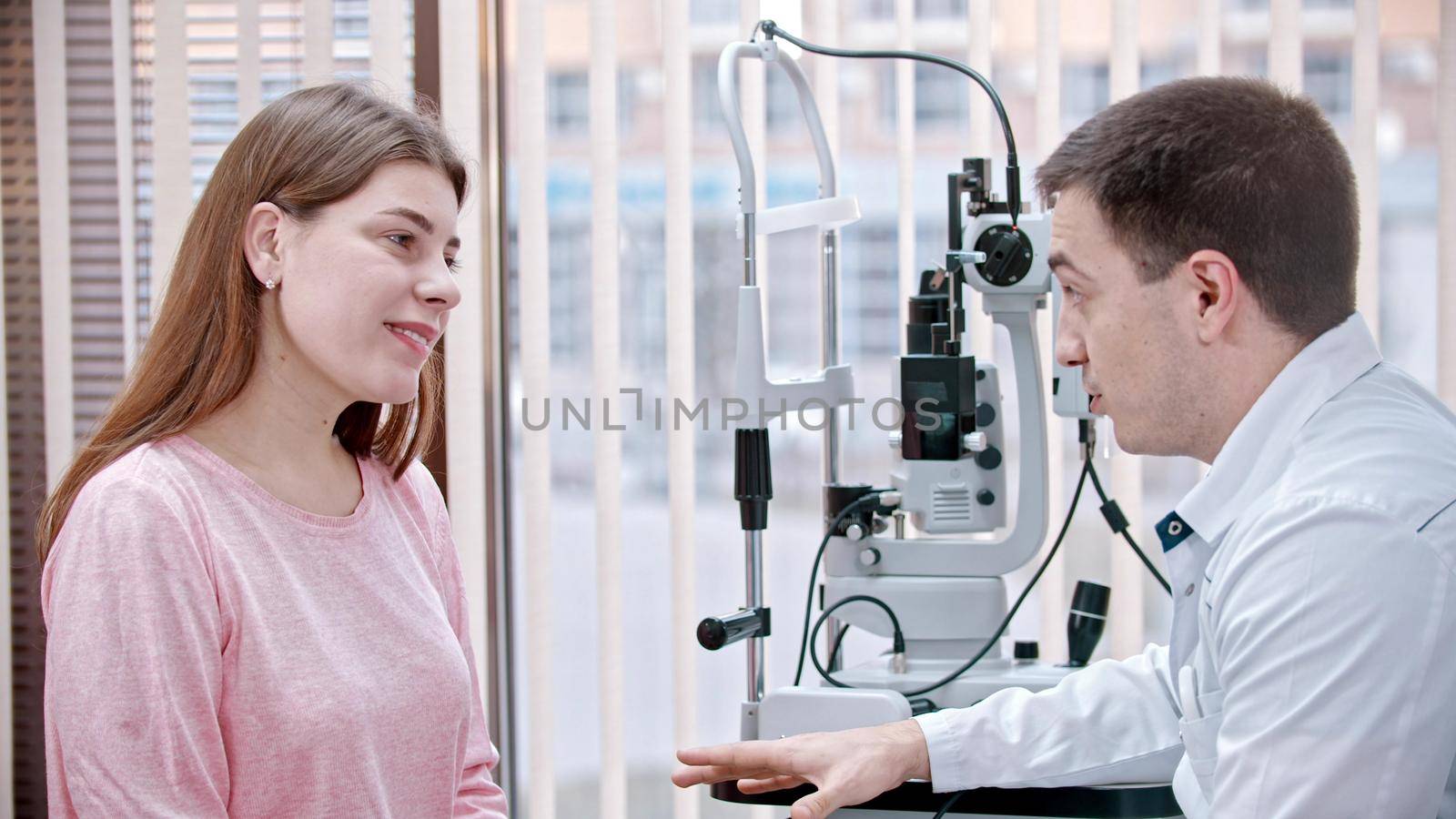 Ophthalmology treatment in the cabinet - young woman having a consultation with an optometry doctor. Mid shot