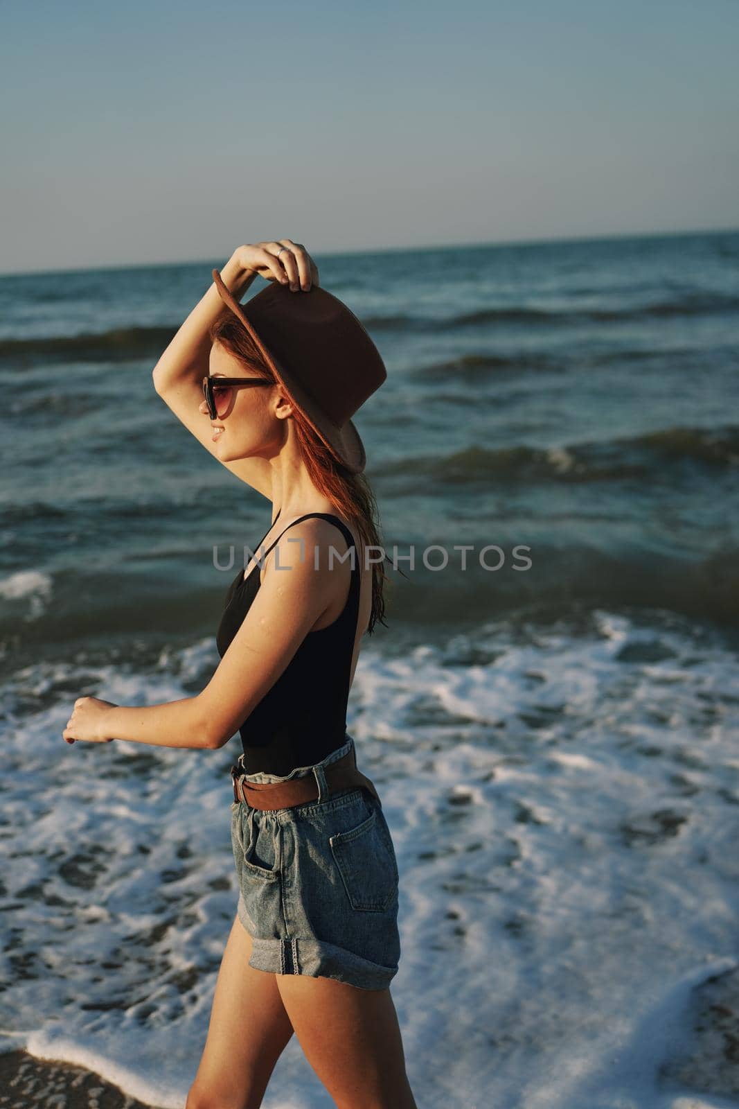 cheerful woman in sunglasses and a hat by the ocean walk summer by Vichizh