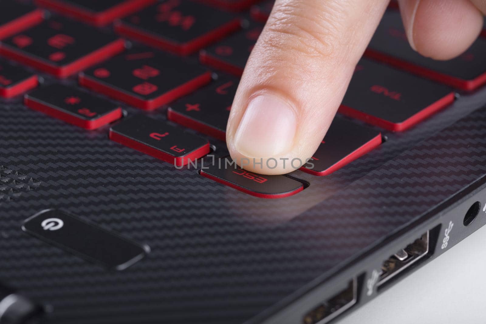 finger pushing esc button on a laptop keyboard