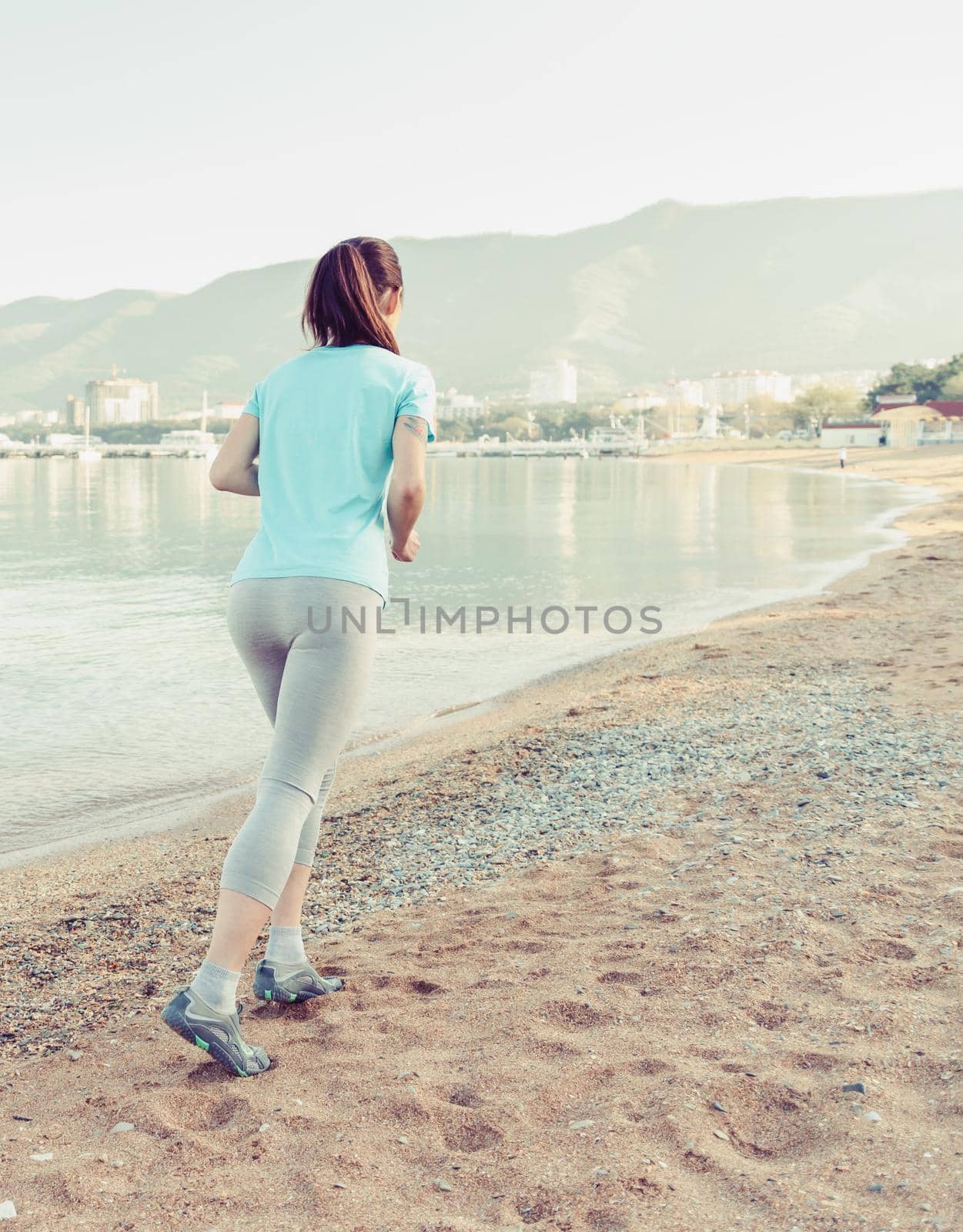 Sporty girl running on sand beach by alexAleksei