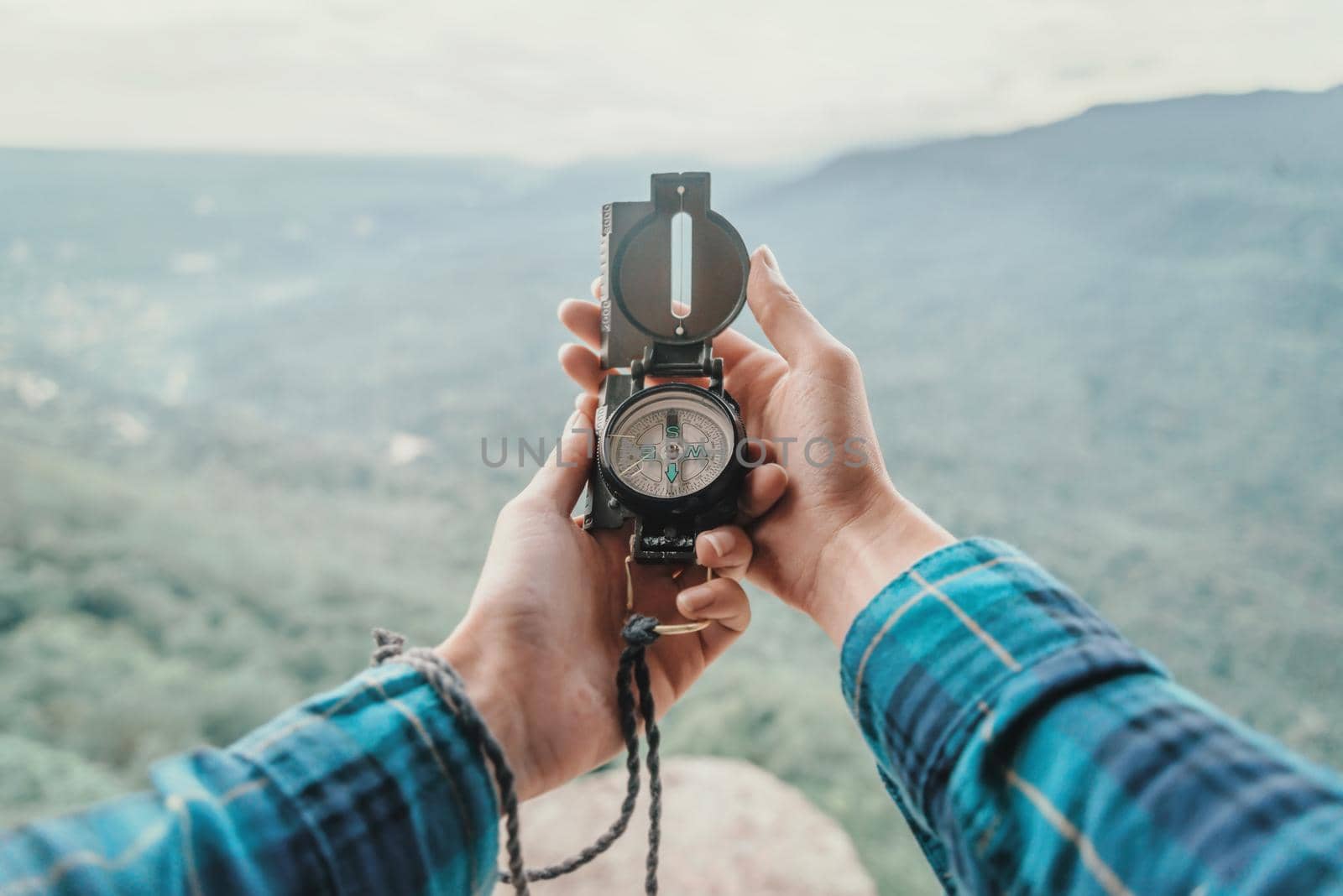 Female traveler searching direction with a compass in the mountains. Point of view shot