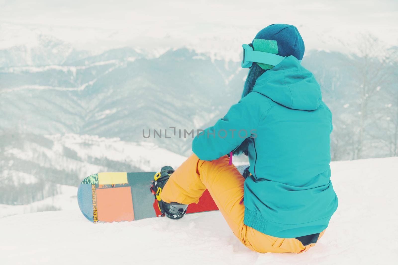 Young woman snowboarder looking at mountains in winter on ski resort