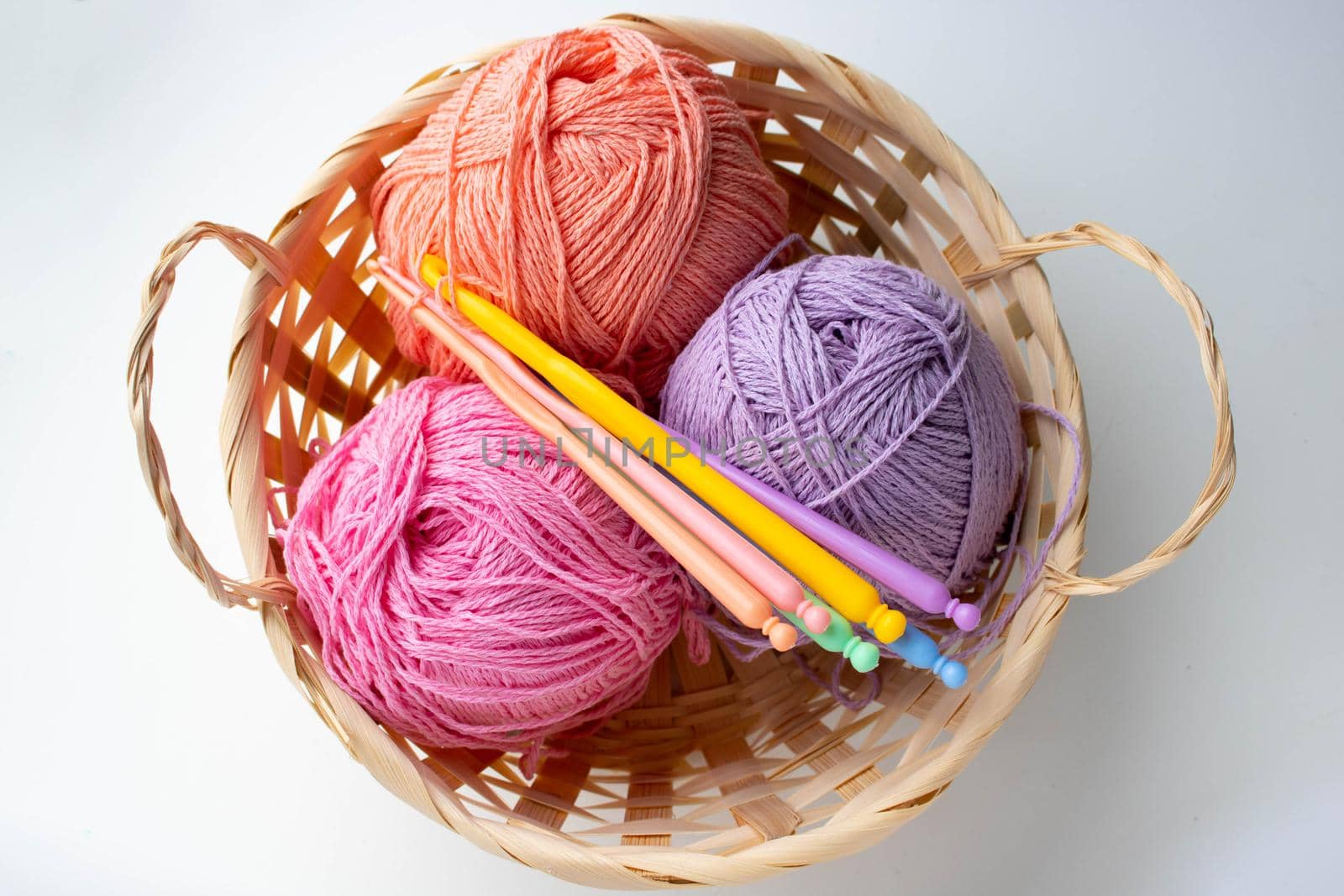 Balls of colored yarn in a basket on white background by lapushka62