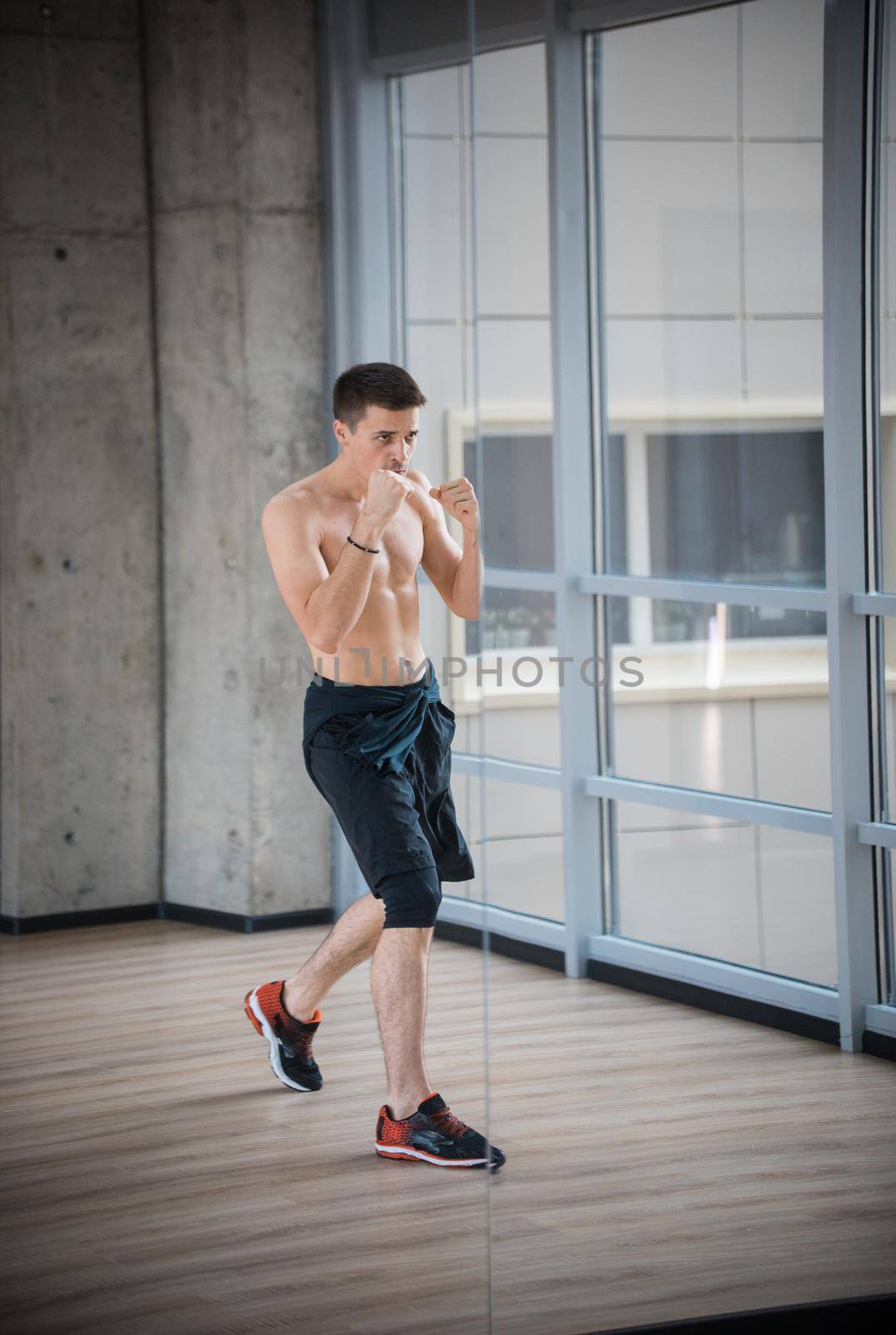 An athletic man boxer standing in fighting protection pose in the studio. Mid shot