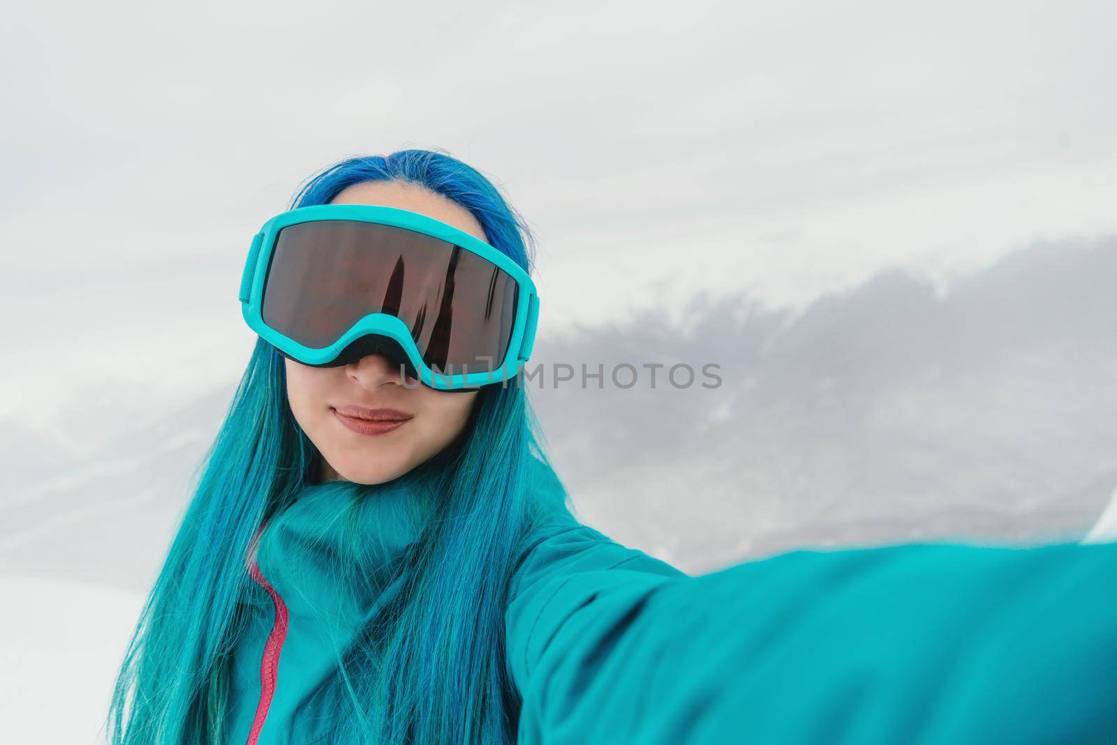 Smiling young woman snowboarder doing selfie in winter outdoor, point of view