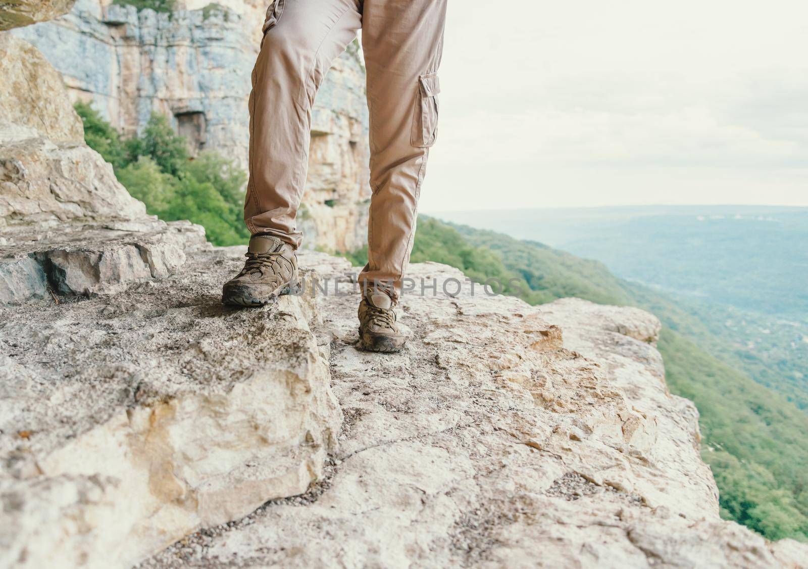 Hiker young woman walking on stone surface outdoor, view of legs